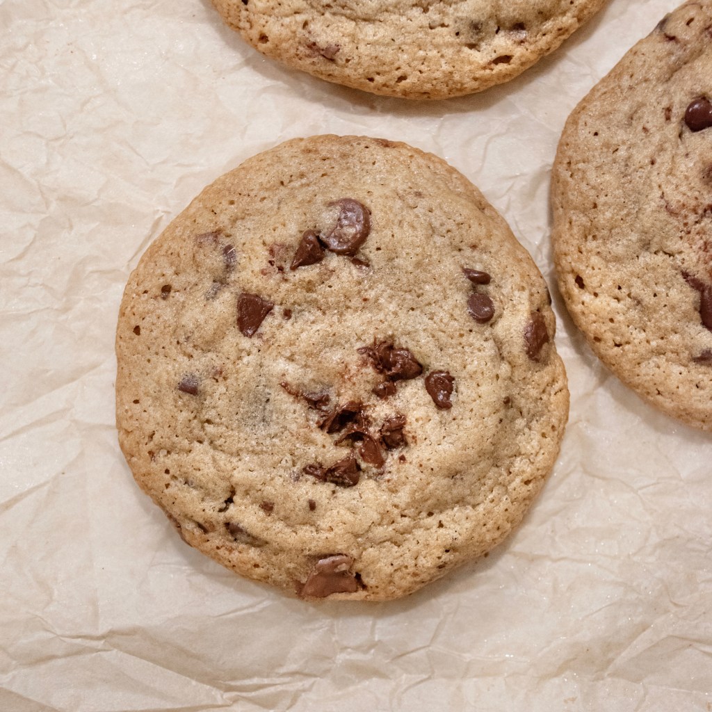 Close-up of freshly baked chocolate chip cookies on parchment paper.